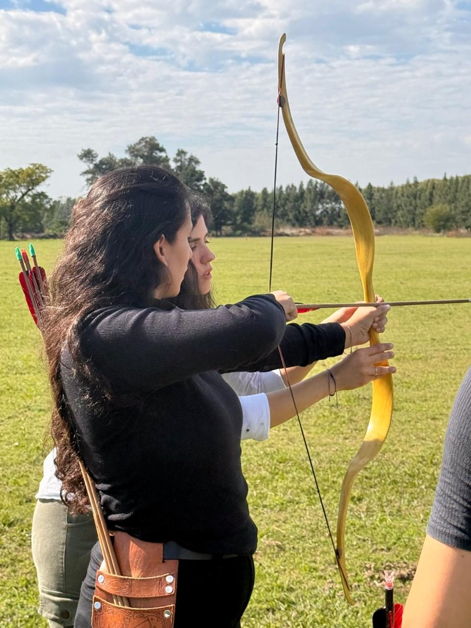 Persona tensando un arco tradicional en el campo